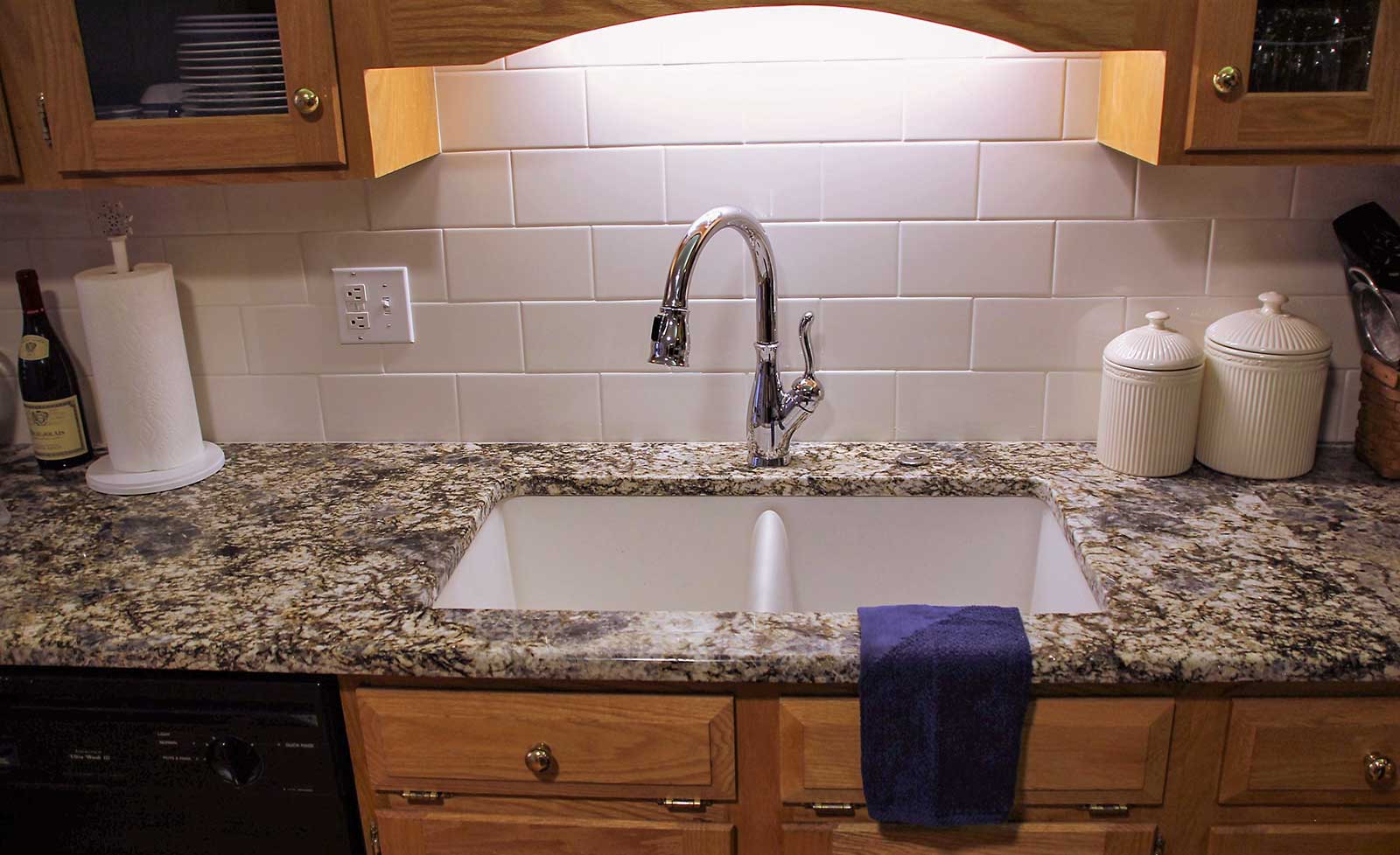 Close-up of granite countertop, subway tile backsplash, and under-counter double sink